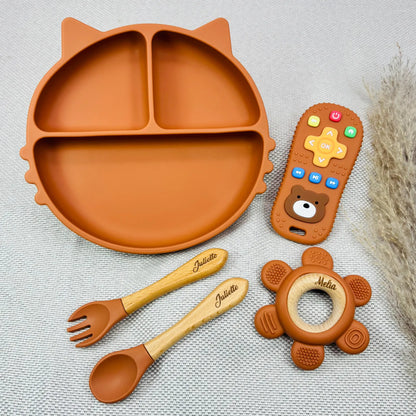Coffret repas bébé terracotta gravé aux prénoms Juliette et Melia, contenant assiette ventouse, couverts bois et jouet bébé en silicone. Parfait pour cadeau personnalisé.