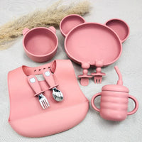 Set repas bébé rose ergonomique en silicone : bol, assiette ours, tasse anti-fuite, bavoir et couverts.