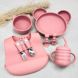 Set repas bébé rose ergonomique en silicone : bol, assiette ours, tasse anti-fuite, bavoir et couverts.