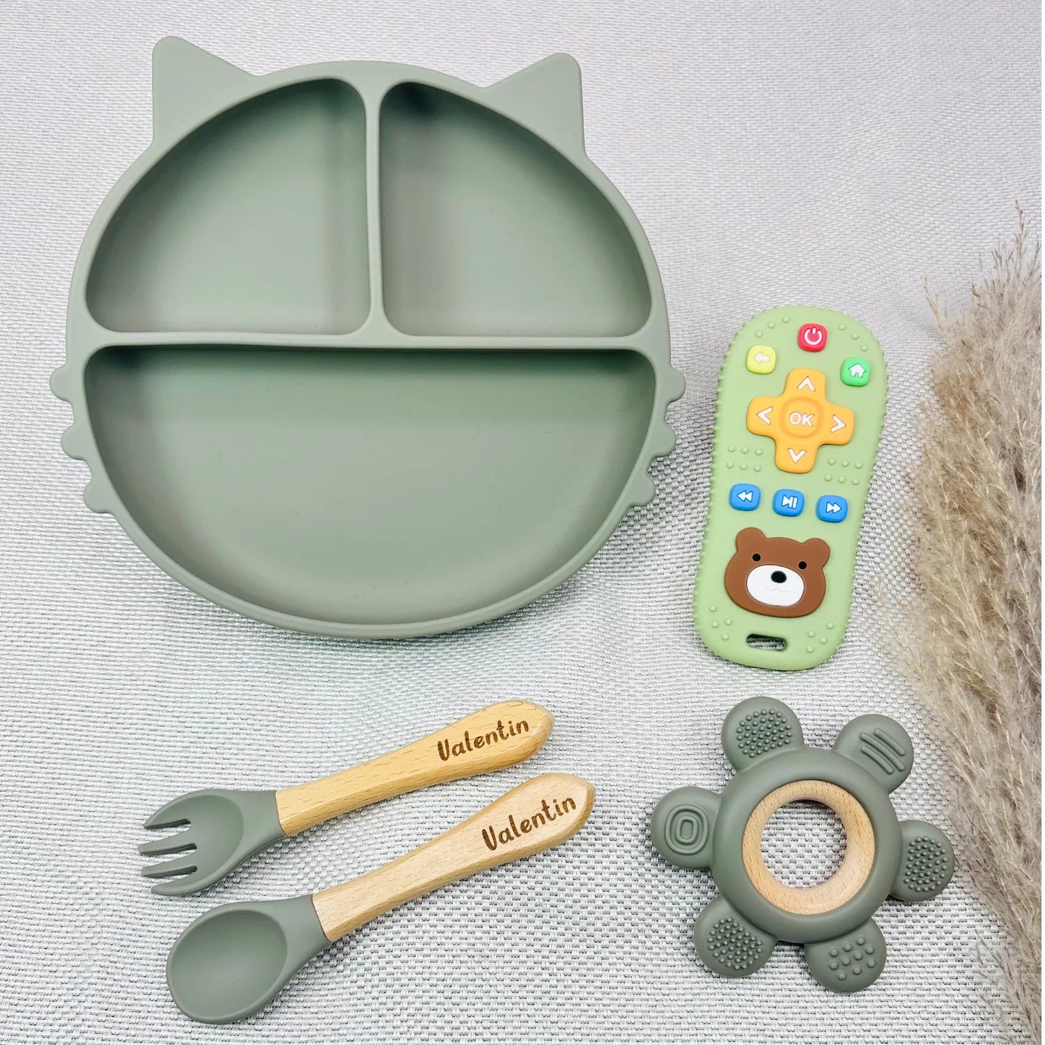 Set repas bébé vert sauge avec prénom Valentin gravé, assiette silicone forme chat, couverts assortis et jouet de dentition. Coffret pratique et original pour bébé.